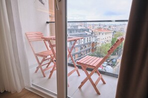 Un balcón con mobiliario de madera y vista a la ciudad.