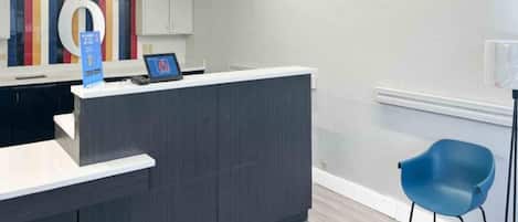 Una reception con una scrivania, una sedia blu e una decorazione murale colorata.