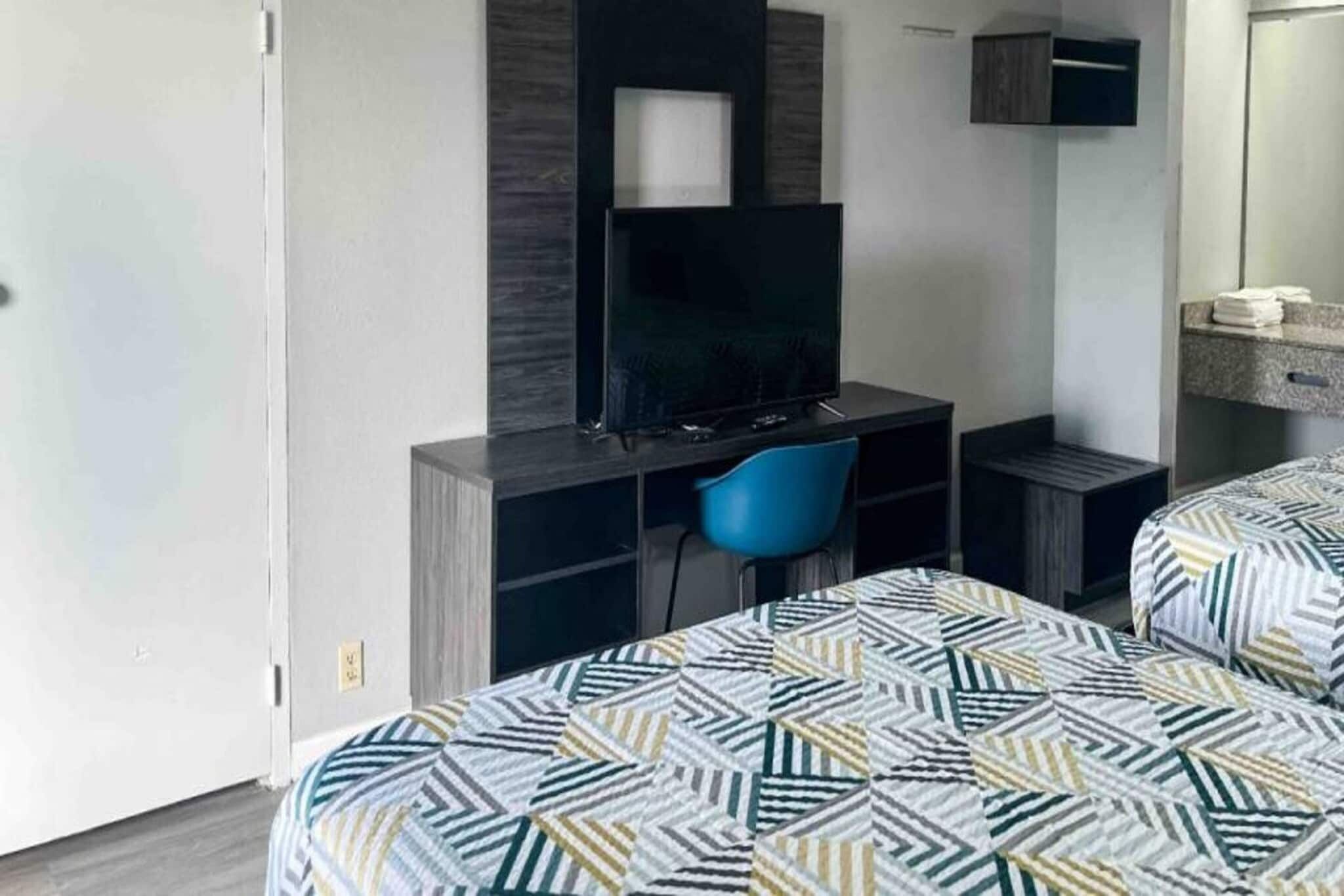Une chambre d’hôtel comprenant un lit, un bureau avec une chaise, une télévision et un miroir.