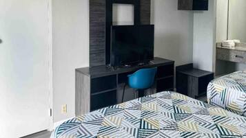 Une chambre d’hôtel comprenant un lit, un bureau avec une chaise, une télévision et un miroir.