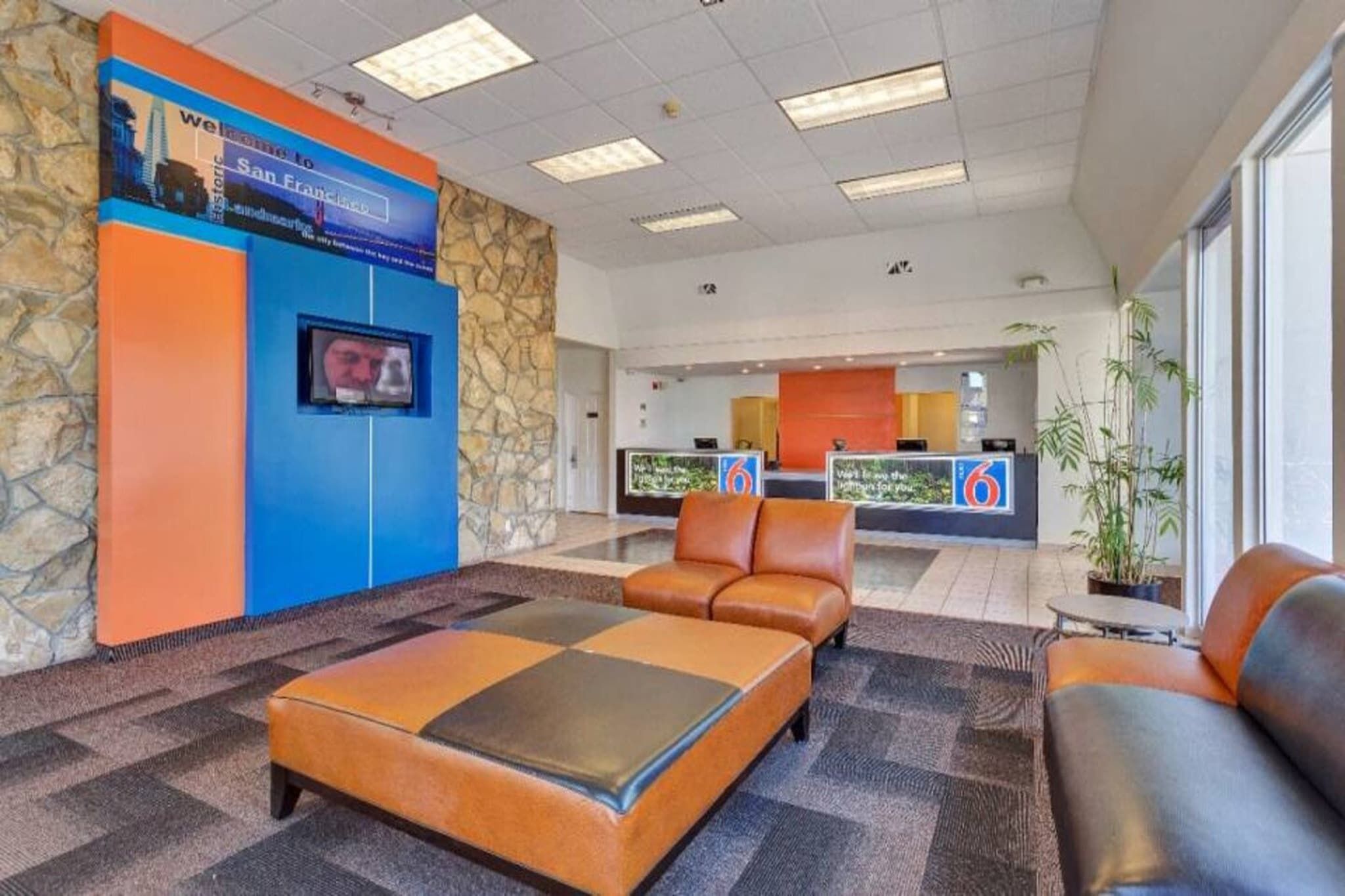 Eine Lobby mit einer Rezeption, einer Sitzecke und einer Steinwand.