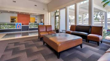 A lobby with a reception desk, seating area, and large windows.