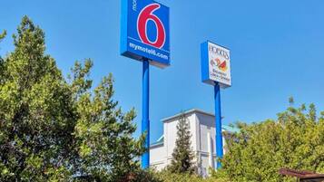 Schild eines Motels mit der Nummer 6 und ein nahegelegenes Schild für ein Restaurant namens 'HOBEES', das Frühstück, Mittagessen und Abendessen anbietet.