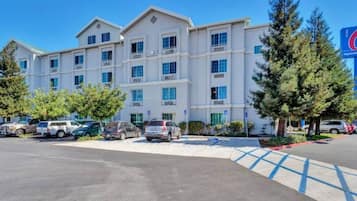 A multi-story hotel with a parking lot in front.