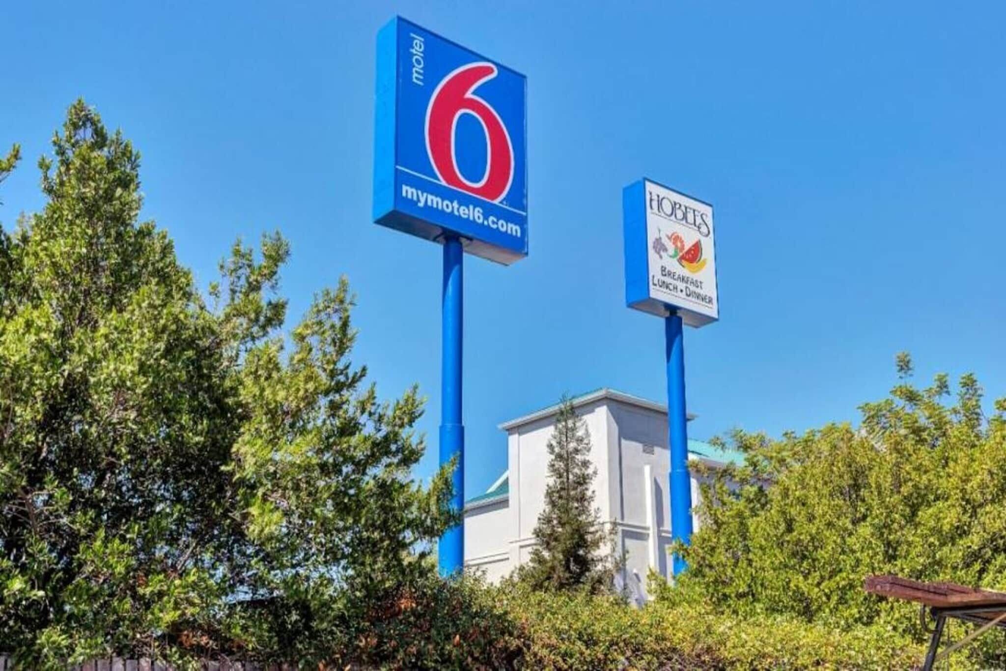 A motel sign with the number 6 and a nearby sign for a restaurant named 'HOBEES' offering breakfast, lunch, and dinner.