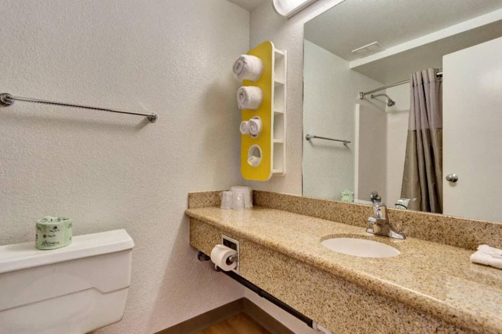 A bathroom with a sink, mirror, towel rack, toilet, and a shower curtain.