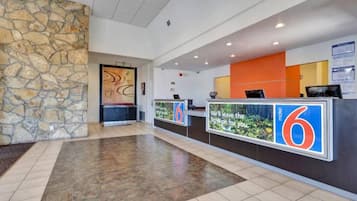 A hotel reception area with a stone wall, a reception desk, and a tiled floor.