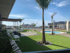 A pool area with a chessboard, lounge chairs, and palm trees. - Your Private Coastal Escape in Ballito, Dolphin Coast Bliss (Dolphin Coast)