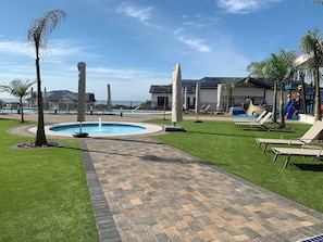 Un área de piscina con sillones, un sendero y un edificio de diseño moderno.