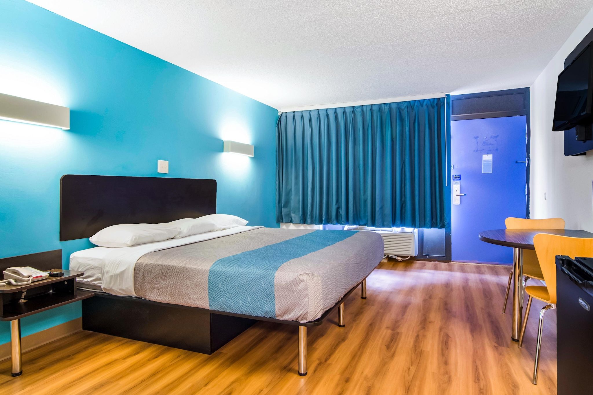 Een hotelkamer met een bed, nachtkastje en een bureau met een stoel.