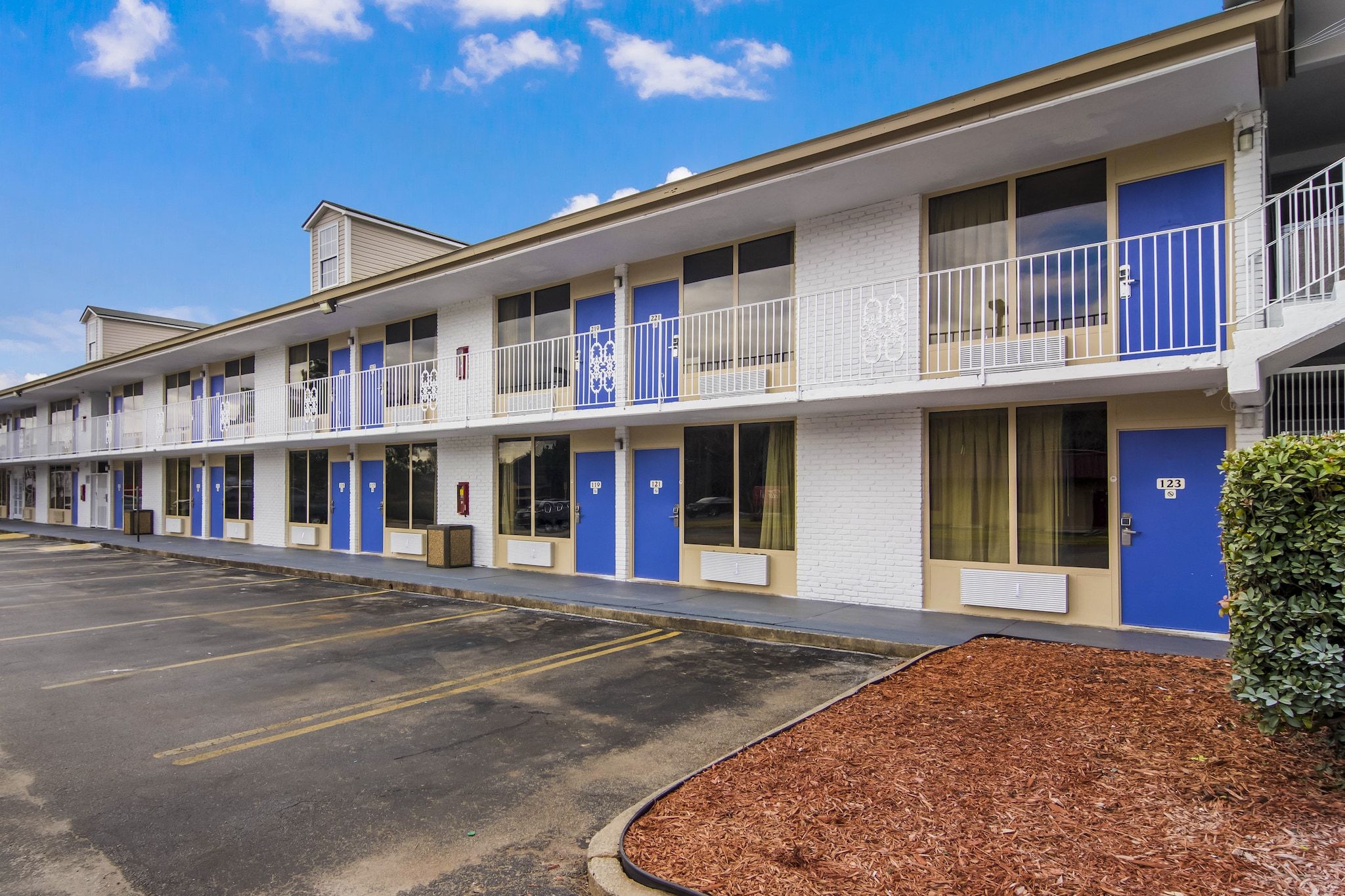 A motel with multiple rooms, each with a blue door and a balcony.