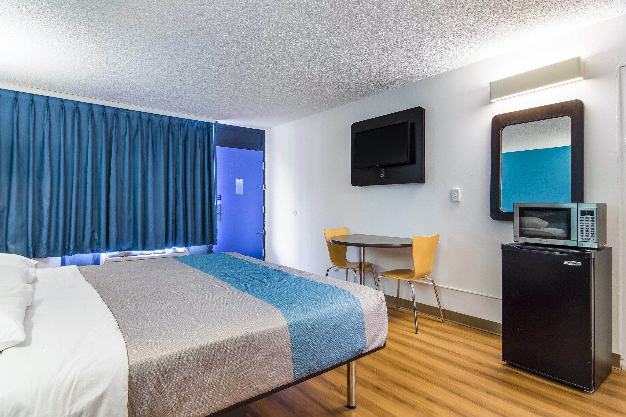 Une chambre d’hôtel équipée d’un lit, d’un bureau, d’une chaise, d’une télévision et d’un mini-bar.