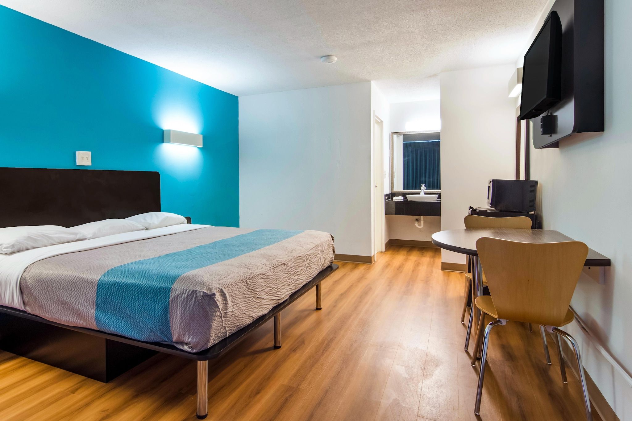 A hotel room with a bed, a desk, and a TV.