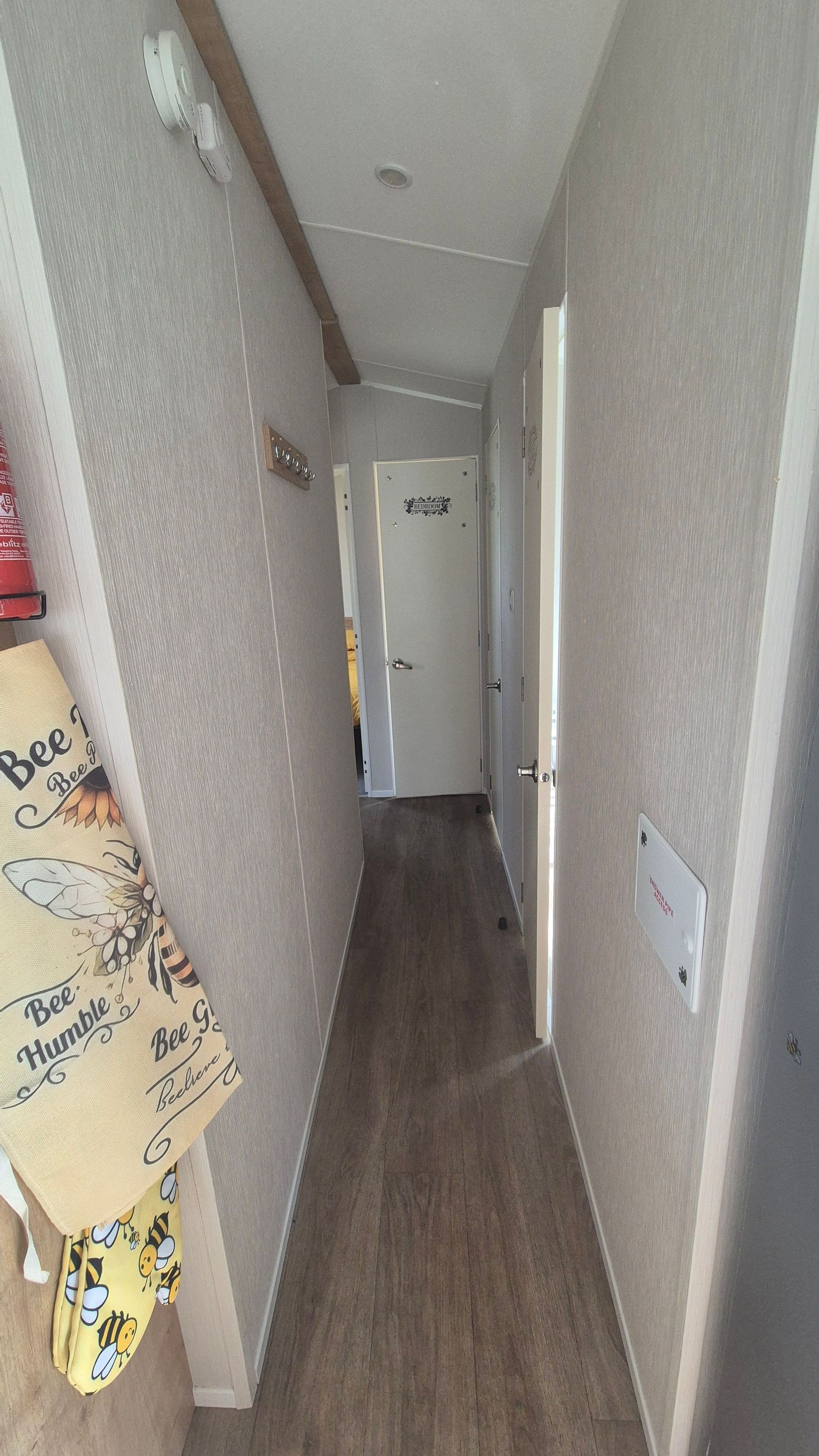 A hallway with a door labeled 'Bedroom' and a wall-mounted smoke detector.