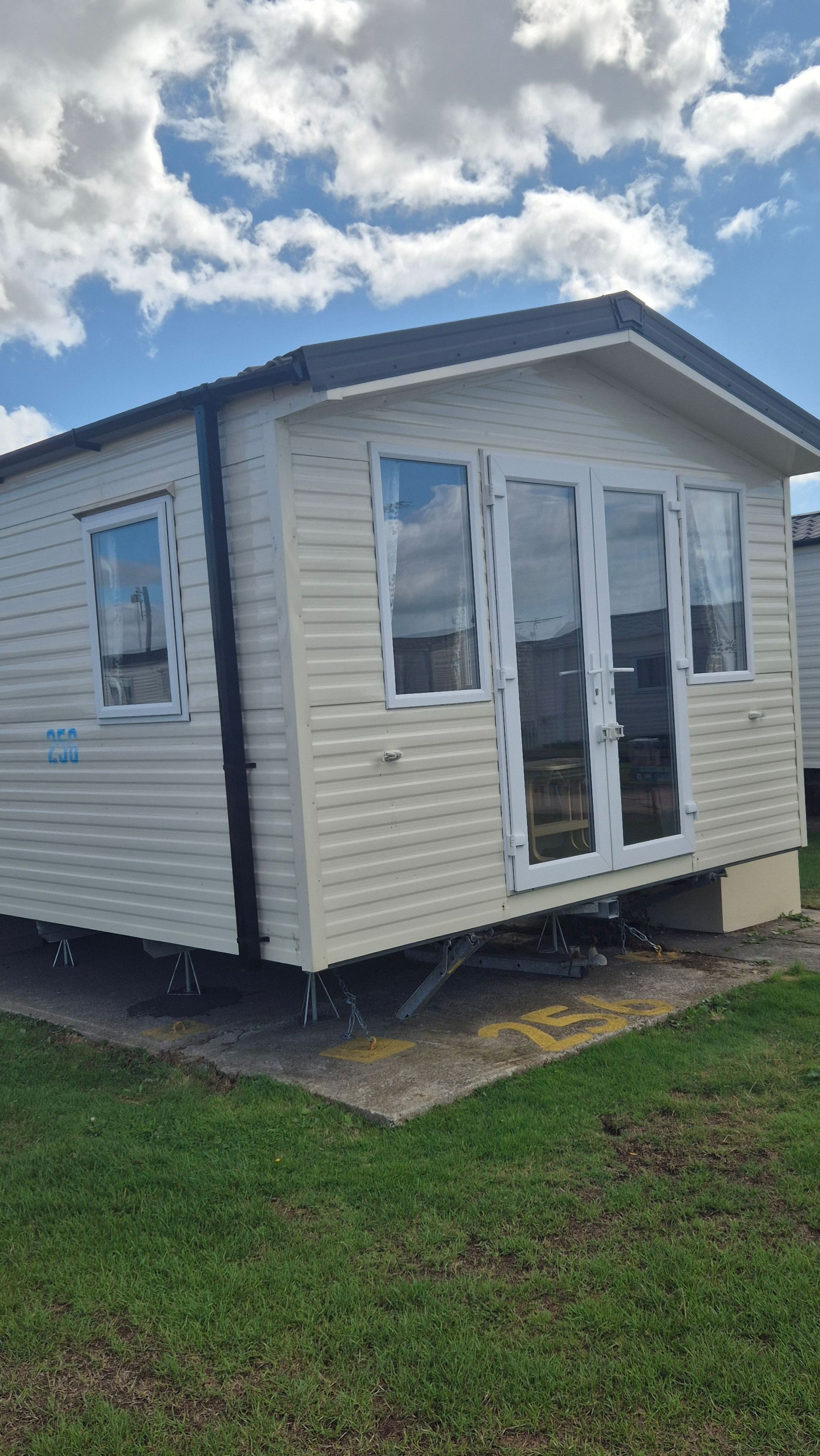 A single-story mobile home with a front door, two windows, and a small porch area.