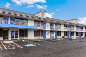 A motel with multiple rooms, a parking lot, and a blue awning.