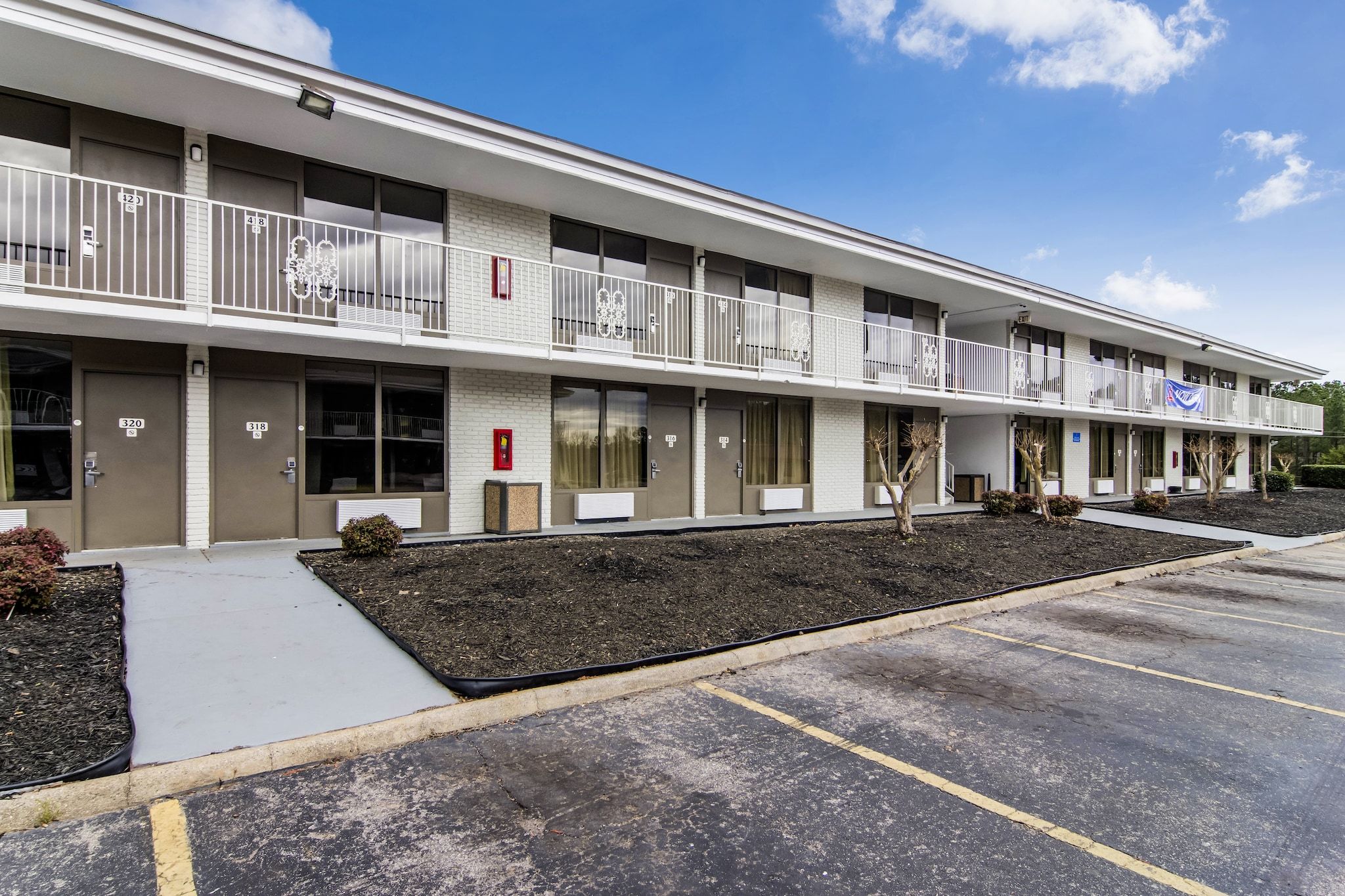 Un motel à plusieurs étages, doté de chambres individuelles, d’un parking et d’un petit espace aménagé.