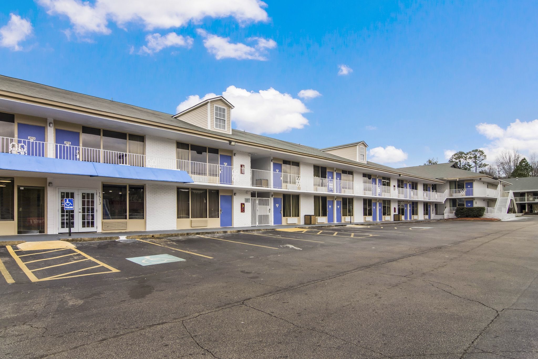 A motel with multiple rooms, a parking lot, and a clear sky.