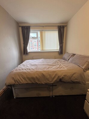 A bedroom with a single bed, a window with curtains, and a radiator. - Double room upstairs R2 (Woodhouse)