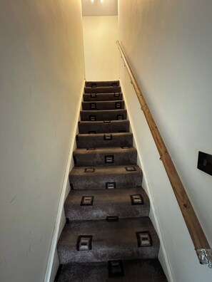 A staircase with carpeted steps and a wooden handrail. - Double room upstairs R2 (Woodhouse)