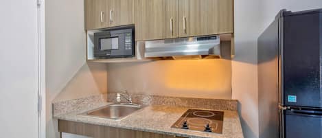 A compact kitchen with a microwave, stove, sink, and refrigerator.