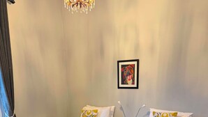 A hotel room with two beds, a chandelier, a framed picture on the wall, and a window with curtains. - The historical Bank house 2 (Lawrence)