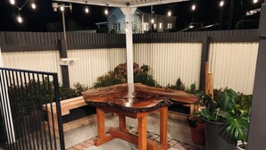 An outdoor patio area with a wooden table and chairs, surrounded by potted plants and a metal fence. - The historical Bank house 2 (Lawrence)