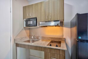 A compact kitchen with a microwave, stove, sink, and refrigerator. - 1 Queen Bed | Non-Smoking (Austin)