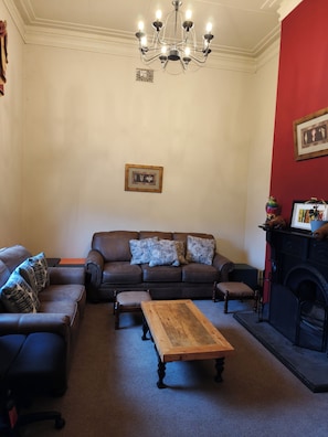 A living room with a brown leather sofa, a wooden coffee table, and a fireplace. - The historical Bank house 3 (Lawrence)