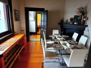 A dining area with a glass table set for six, surrounded by white chairs. - The historical Bank house 3 (Lawrence)