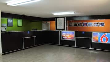 A hotel reception area with a green wall, black reception desk, and a sign that reads 'Welcome Home!'.