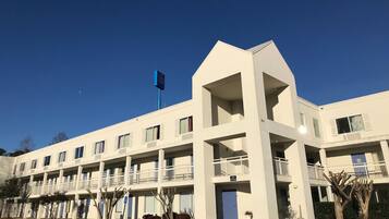 Ein mehrstöckiges Hotel mit flacher Fassade, Balkonen und einer Flagge.