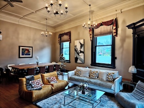 A living room with a sofa, armchairs, a coffee table, and a dining area with a table and chairs. - The historical Bank house 4 (Lawrence)