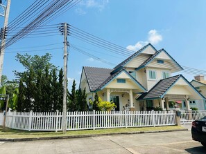 A two-story house with a white picket fence, a tiled roof, and a car parked in front. - The Oasis Pool Villa (Chiang Mai)