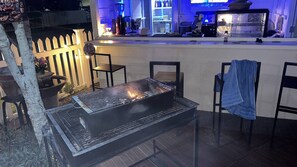 An outdoor bar area with a grill, seating, and a counter with various items. - The Oasis Pool Villa (Chiang Mai)