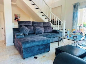 A living room with a sectional sofa, a glass coffee table, and a staircase. - The Oasis Pool Villa (Chiang Mai)