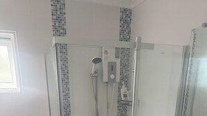Ett modernt badrum med en dusch som är avskärmad med glasväggar, en toalett och ett handfat.