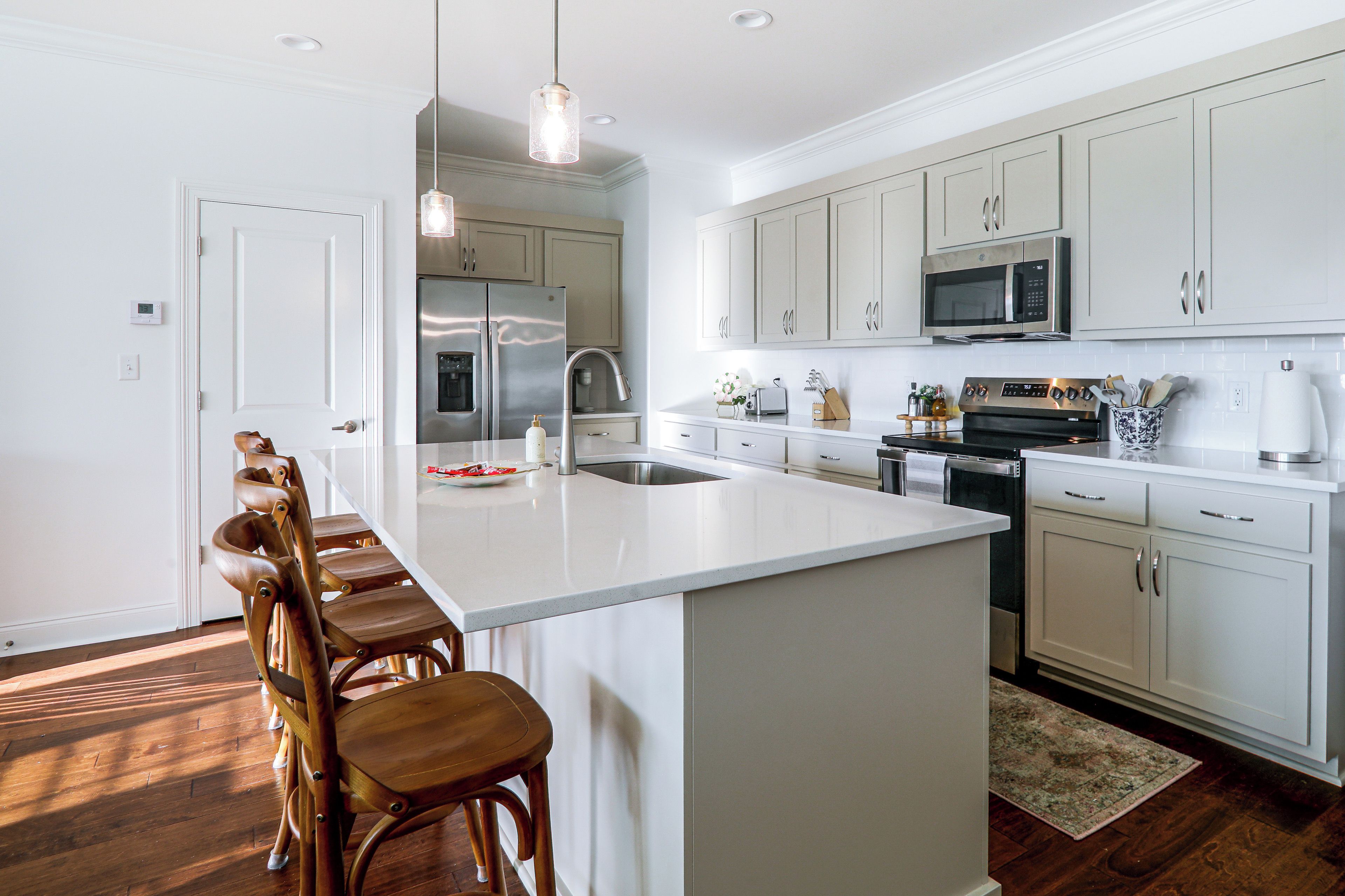 A modern kitchen with a central island, stainless steel appliances, and wooden bar stools.