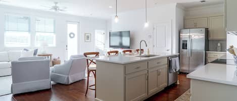 A modern kitchen with a central island, built-in appliances, and a dining area with a TV.
