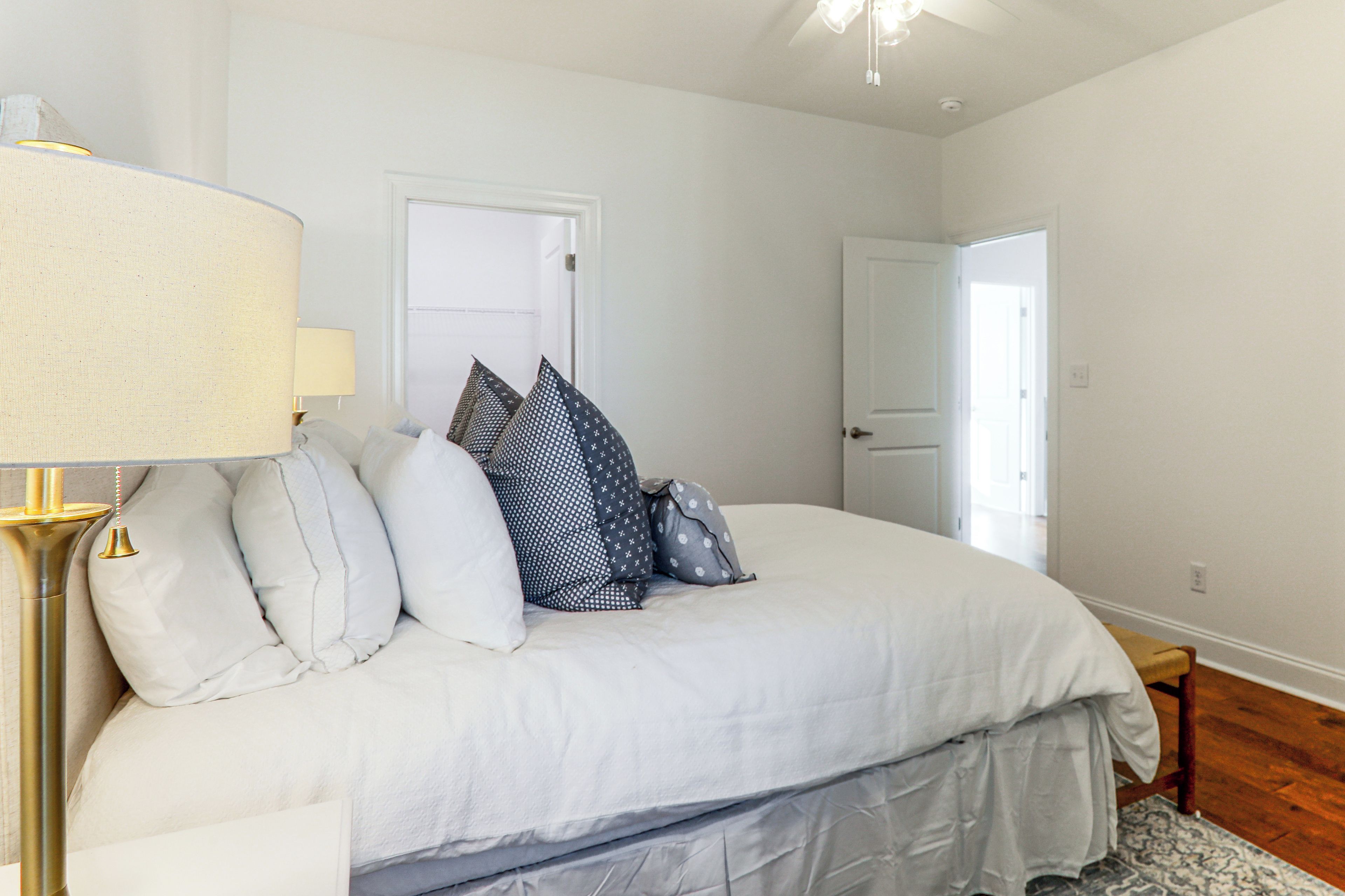 Un dormitorio con cama, almohadas, una lámpara y una puerta.