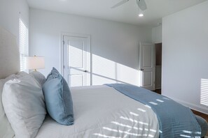 Ein Schlafzimmer mit einem Bett, Kissen, einem Nachttisch, einer Lampe und einem Deckenventilator.