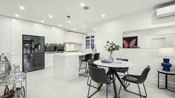 A modern kitchen with white cabinetry, a central island, and a dining area with a round table and chairs.