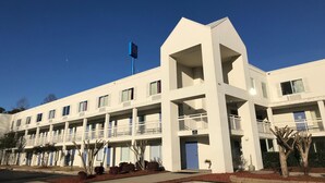 Ein mehrstöckiges Hotel mit flacher Fassade, Balkonen und einer Flagge.
