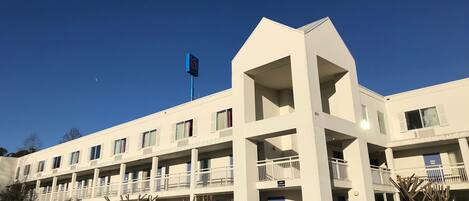 Un hôtel à plusieurs étages, doté d’une façade sobre, de balcons et d’un drapeau.