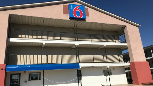 Ein Motel mit auffälligem '6'-Schild, mehreren Balkonen und einem Parkplatz.