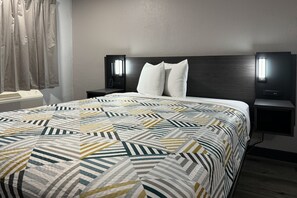 A hotel room with a large bed, two bedside tables, a wall-mounted phone, and a window with curtains. - Cozy Queen Bed ADA | Pool|Free Wifi (FL)