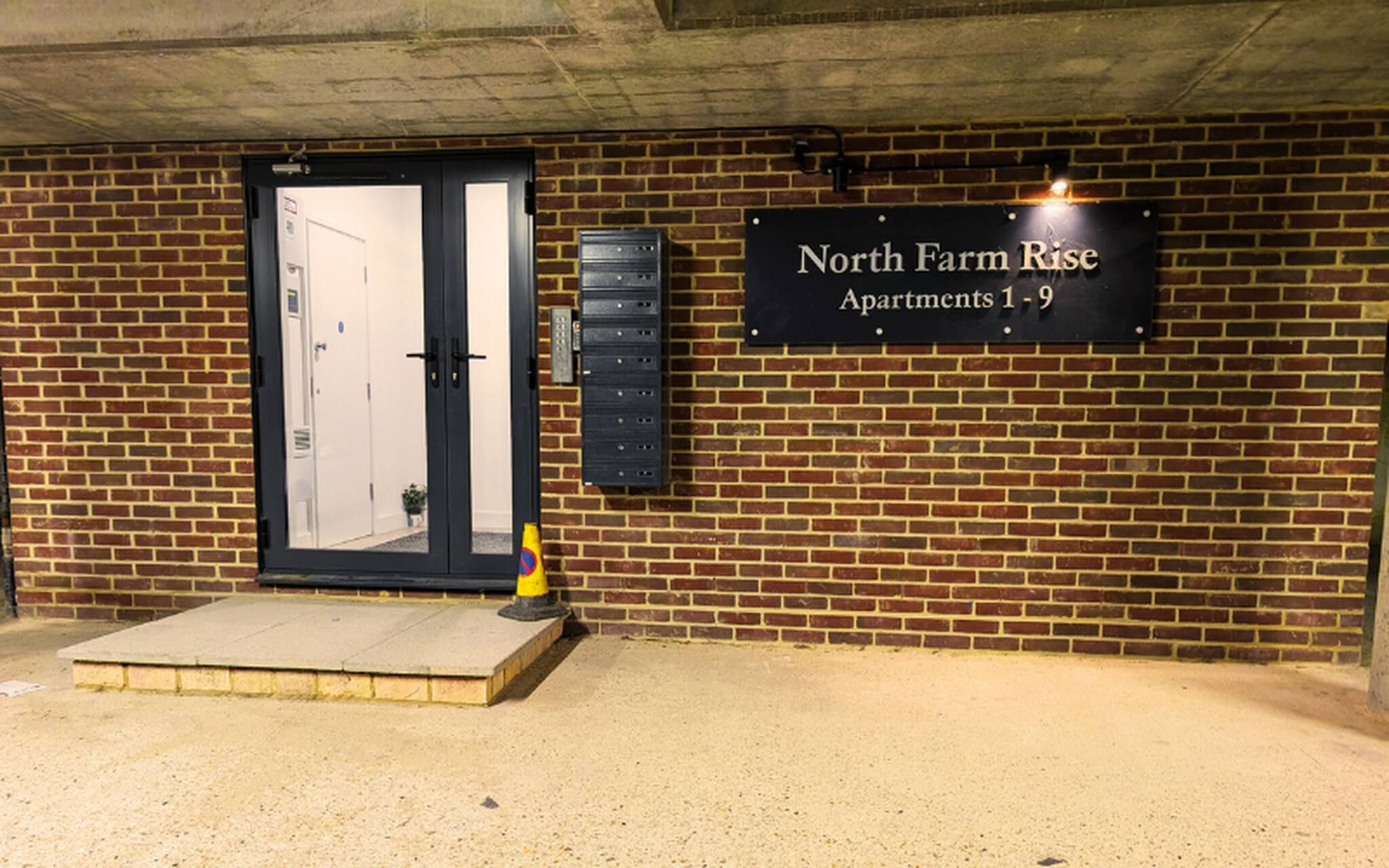 Un edificio de ladrillo con un letrero que indica 'North Farm Rise Apartments 1-9'.