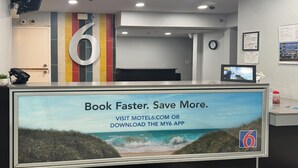 A reception desk with a large sign advertising a mobile app for booking. - Comfort 2 Full Beds | Mini Fridge (Bradenton)