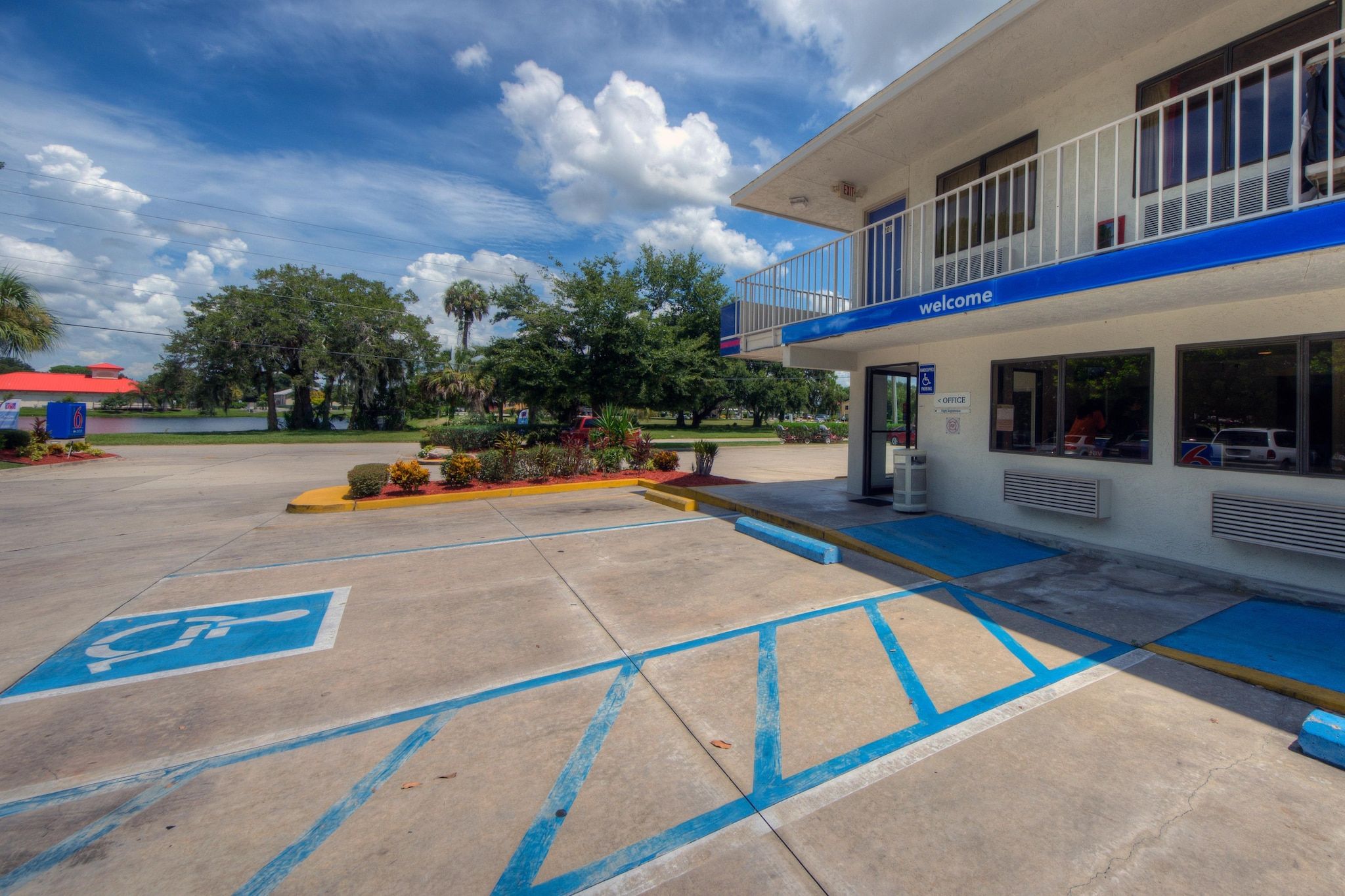 A building with a blue and white exterior, a ramp leading to the entrance, and a parking lot with blue handicapped parking spaces.