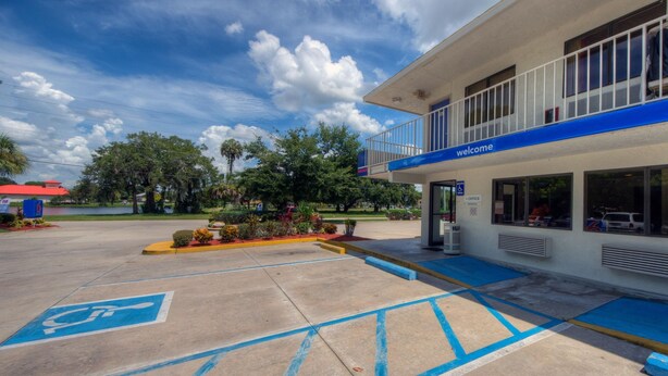 A building with a blue and white exterior, a ramp leading to the entrance, and a parking lot with blue handicapped parking spaces. - Comfort 2 Full Beds | Mini Fridge (Bradenton)